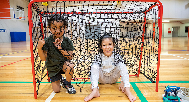 a young boy and girl sitting in a soccer goal 