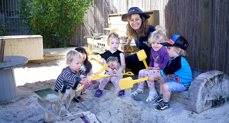 Kauri Kids teacher with 5 children in sandpit with spades