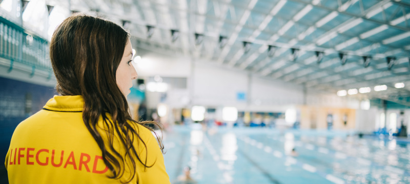 female lifeguard watching the pool with her back towards the camera