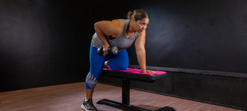 female doing a single arm bent over row on a bench