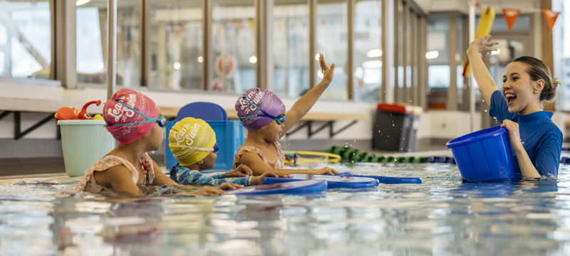 female swim instructor teaching young children to swim