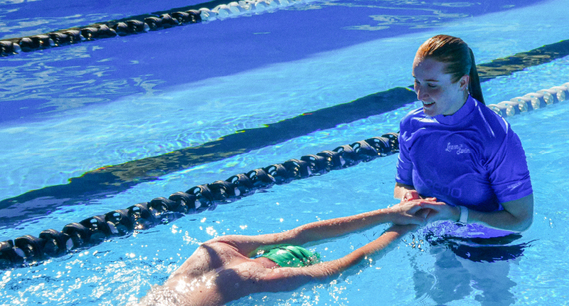 female swim instructor helping male with streamline in the pool